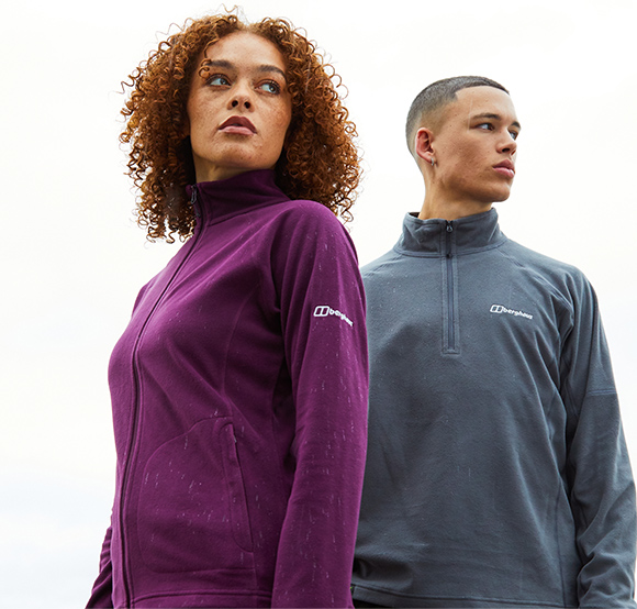 Two models wearing Berghaus fleeces: a woman in a purple full-zip fleece and a man in a grey half-zip fleece.