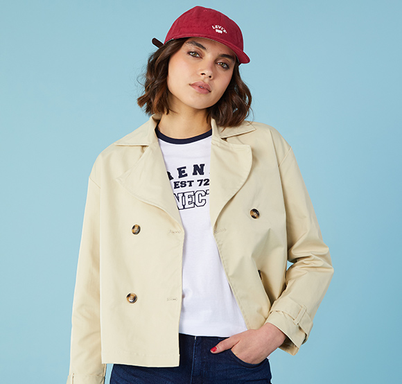 Female model in a hat wearing a smart hip-length jacket.