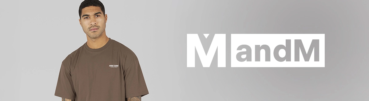 Mann in dunkelgrauem Utility-Overshirt mit Brusttaschen, hellem cremefarbenem Poloshirt und dunkelblauer Hose, sitzend.